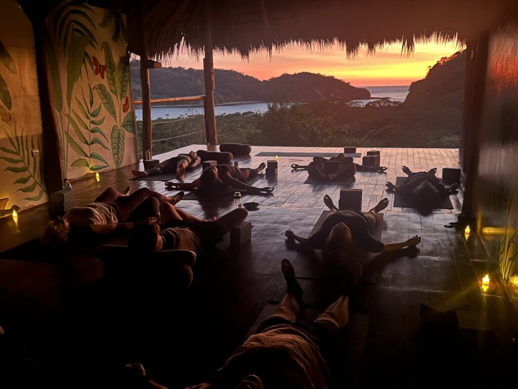 Sunset yoga class overlooking the ocean and jungle, creating a serene and transformative atmosphere for yoga teacher training in Central America.